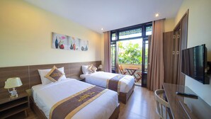 A hotel room with two beds, a TV, a desk, and a balcony with curtains. - Maison Hai Homestay (Da Nang)