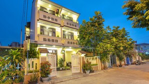 A multi-story hotel with a well-lit entrance, potted plants, and a sign indicating the name. - Maison Hai Homestay (Da Nang)
