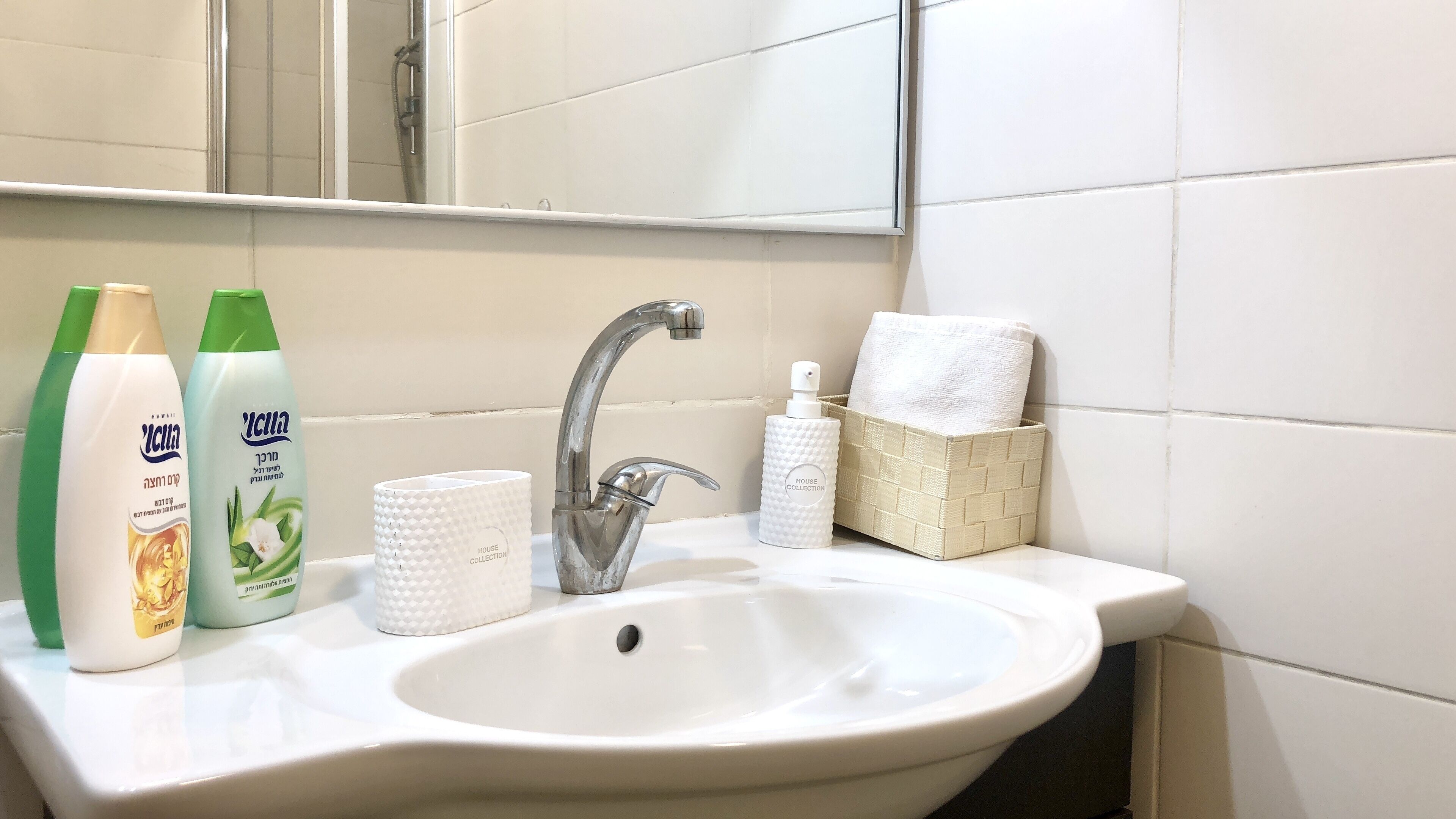 A bathroom sink with toiletries, a towel rack, and a mirror.