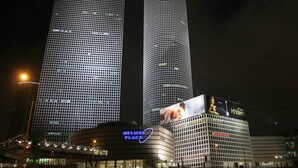 Dos edificios altos, con un anuncio destacado de AHAVA en el lateral de uno de ellos.