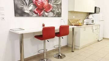 A modern kitchen with white cabinets, a microwave, a toaster, and a red flower painting on the wall.