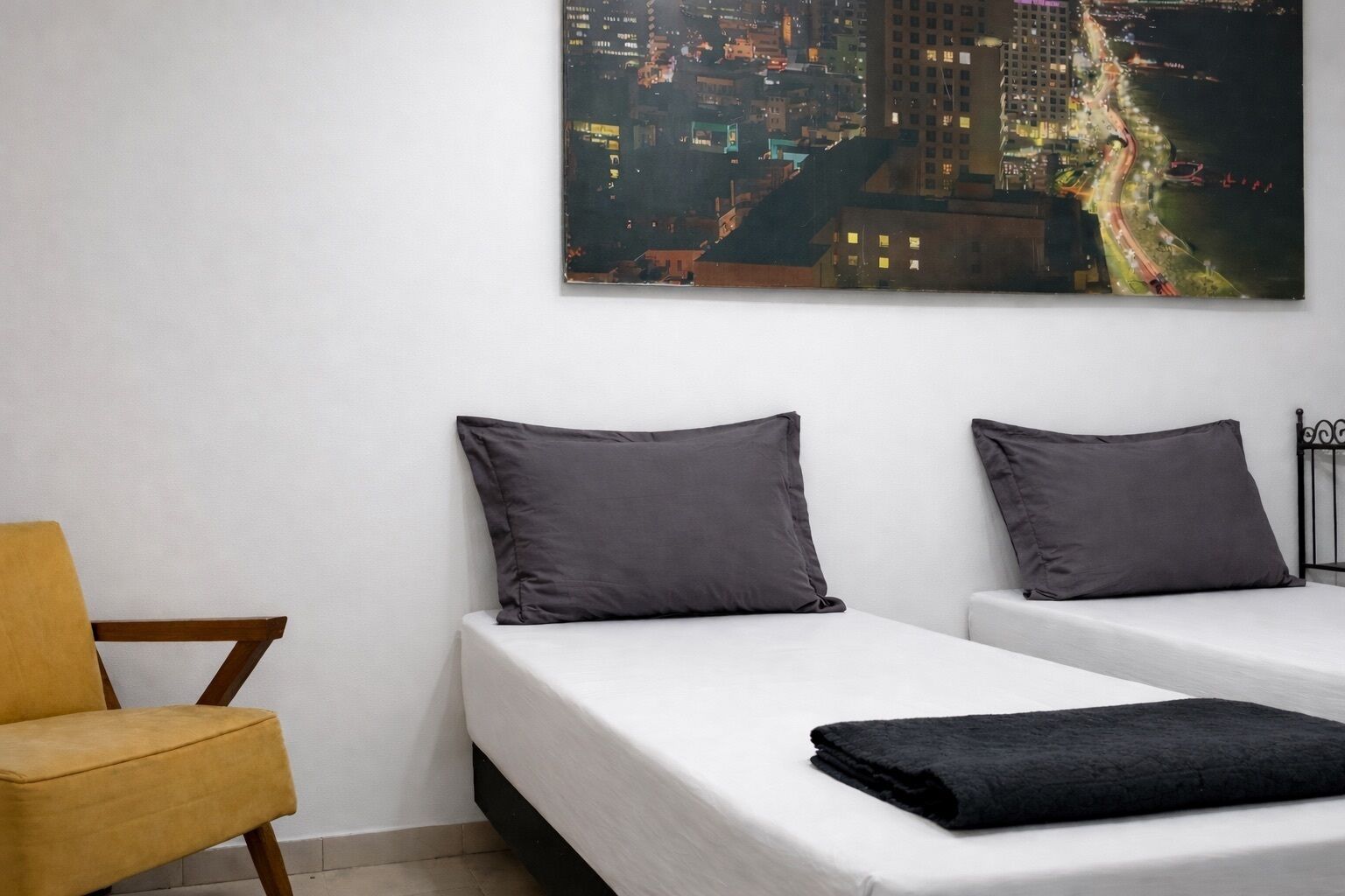 Ett hotellrum med två separata sängar, en stol och utsikt över staden.