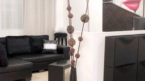 Una sala de estar moderna con un sofá negro, una mesa de centro negra y un jarrón decorativo con adornos esféricos.