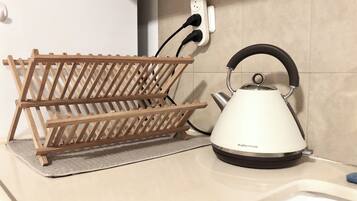 A kitchen with a kettle and a wooden rack.