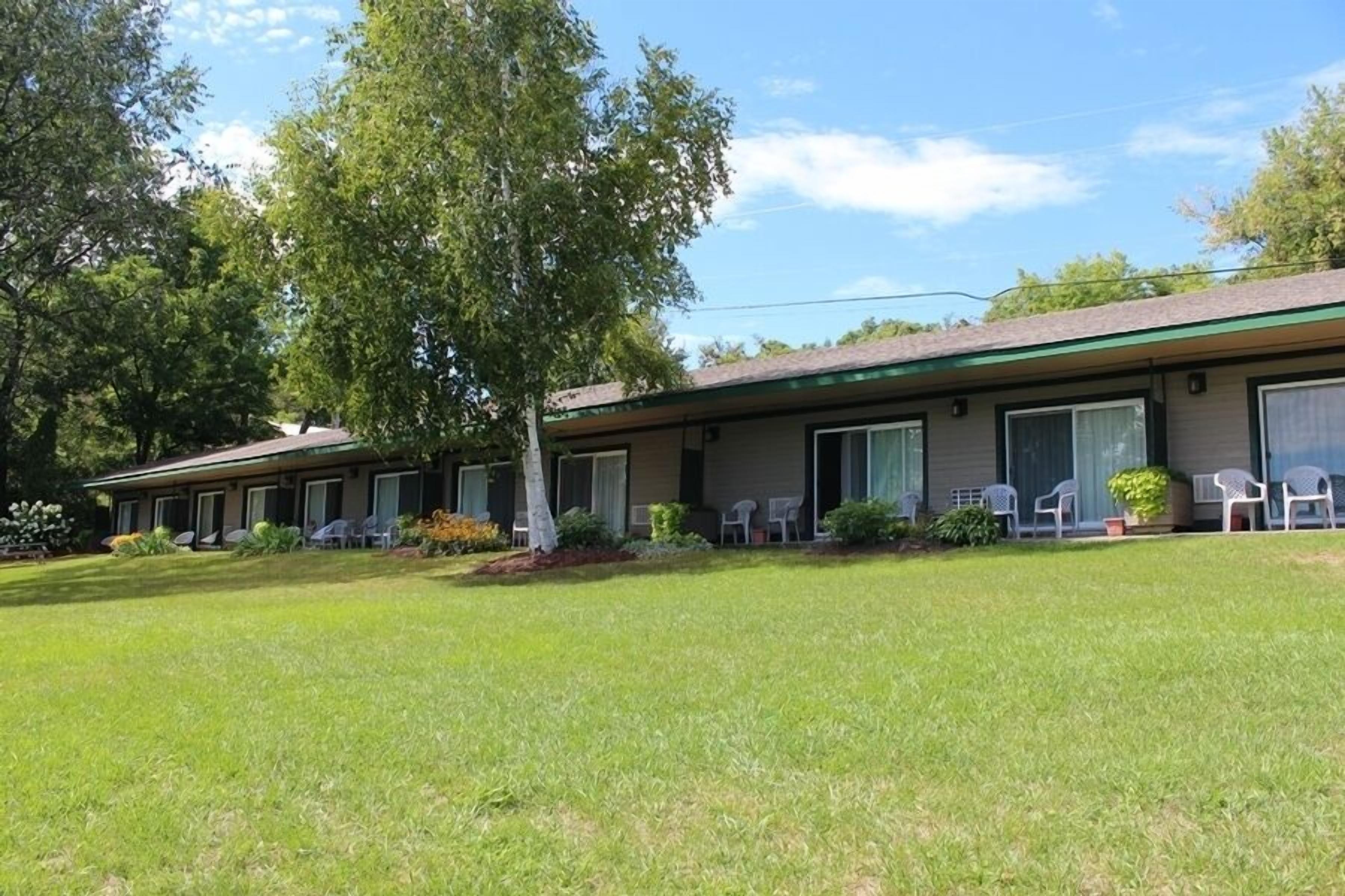 Un motel composé de bâtiments à deux étages, chacun offrant plusieurs chambres et des espaces de détente en plein air.