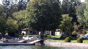 A lakeside residential area with a dock, parked cars, and houses with green shutters. - The Glen House Resort (Leeds and the Thousand Islands)