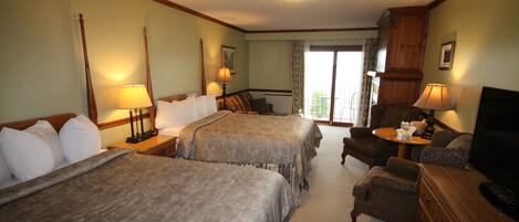 A hotel room with two beds, a sofa, a television, and a balcony with curtains.