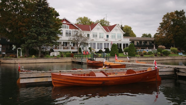 A waterfront property with a dock and several wooden boats. - The Glen House Resort (Leeds and the Thousand Islands)
