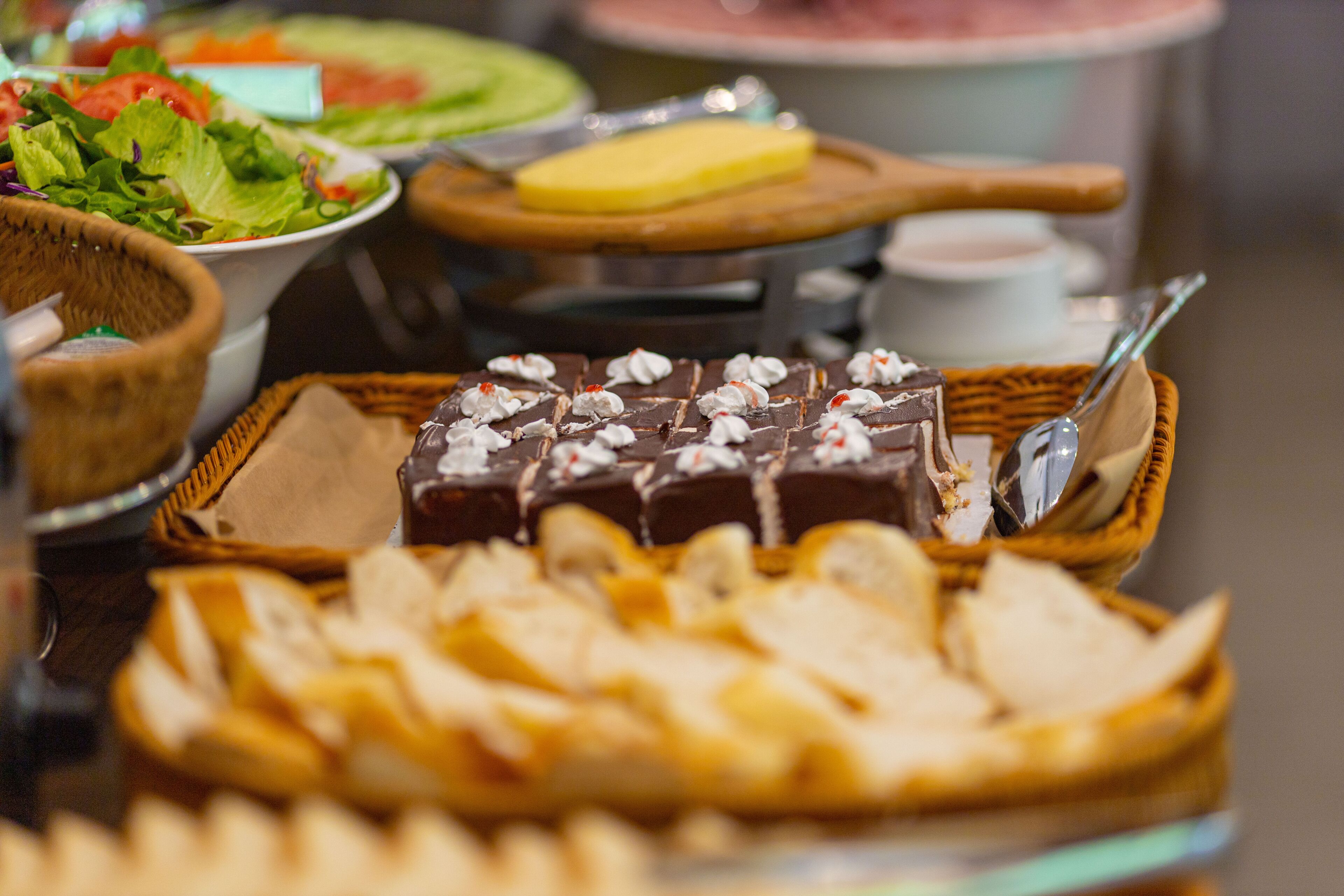 Un buffet proposant une variété de plats, notamment un dessert au chocolat, du pain et une salade.