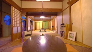 A traditional Japanese room with tatami flooring, a tatami mat table, a heater, and a bookshelf with books and a framed picture.