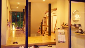 A hotel room with a wooden floor, a staircase, and a bulletin board with a calendar.