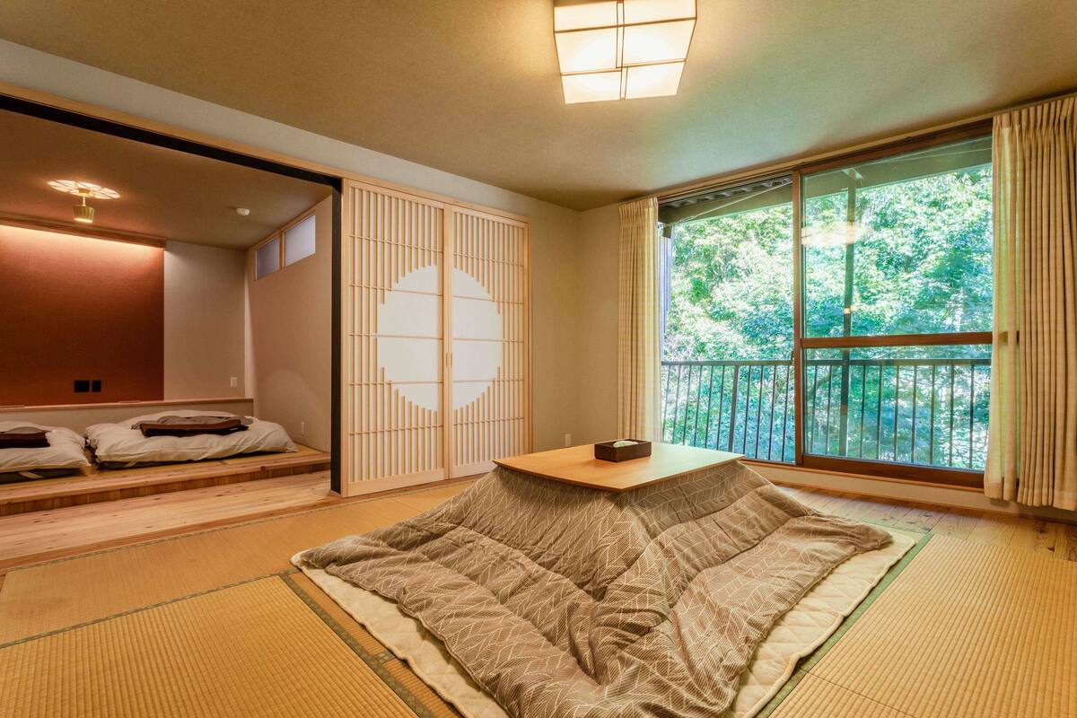 Um quarto japonês tradicional com tatames, uma mesa baixa e uma porta deslizante com padrão geométrico.