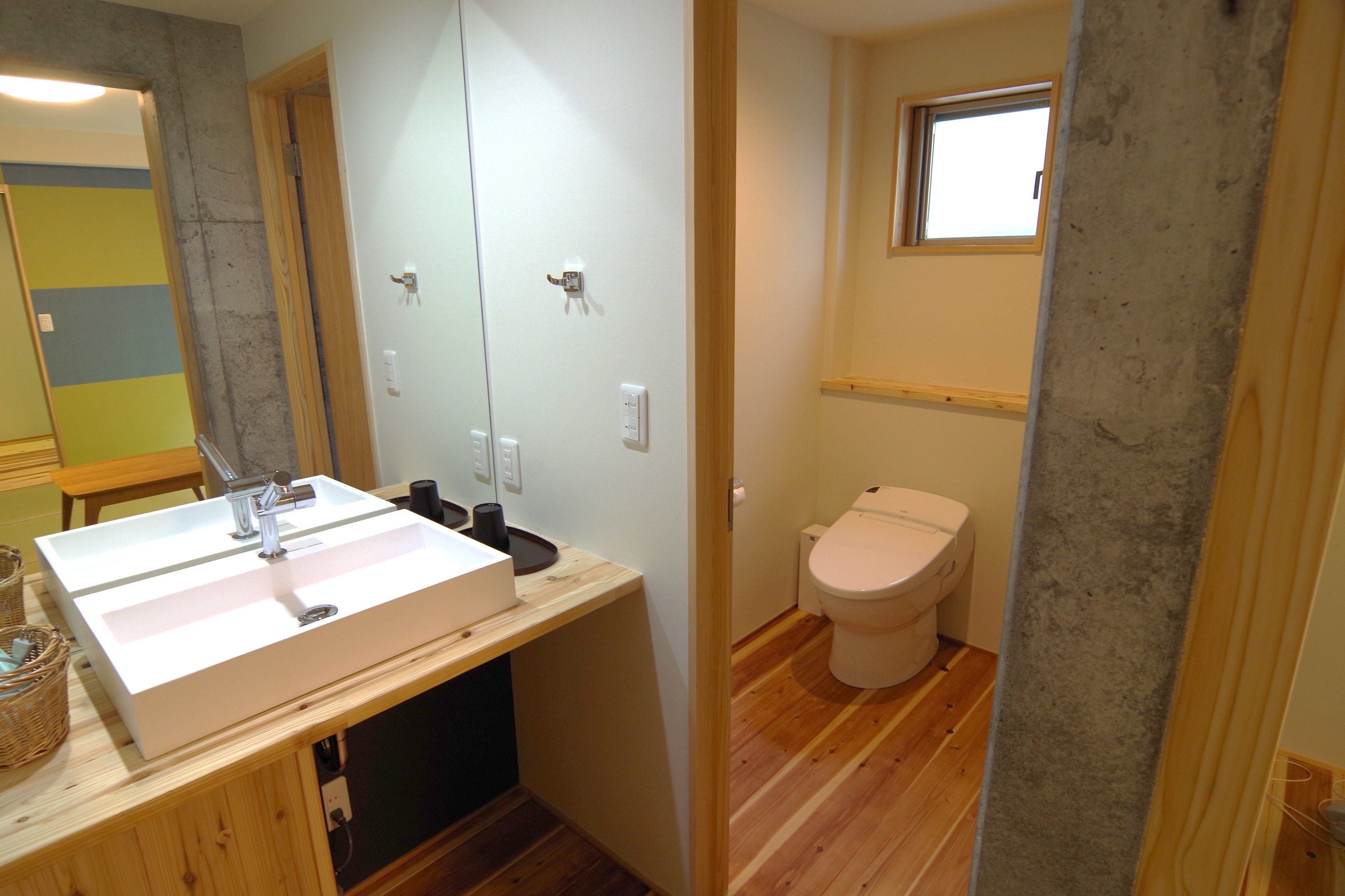 Un bagno con lavandino bianco, mobile contenitore in legno e water.