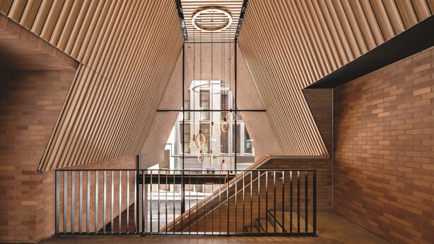 Un intérieur moderne avec un plafond à lattes de bois, des murs en briques et une rambarde en métal.
