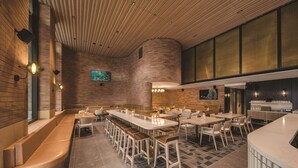 Un restaurant moderne doté d’un long comptoir, de plusieurs espaces de restauration et d’un mur en briques.