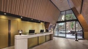 Un comptoir d’accueil au design moderne, une grande fenêtre donnant sur la rue et un plafond en bois.