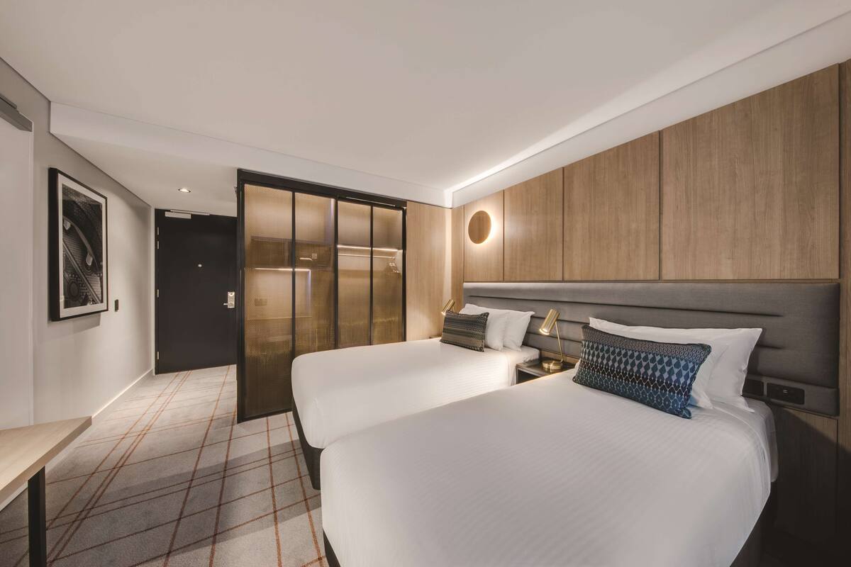 Een hotelkamer met twee bedden, een bureau, een kledingkast en een ronde wandlamp.