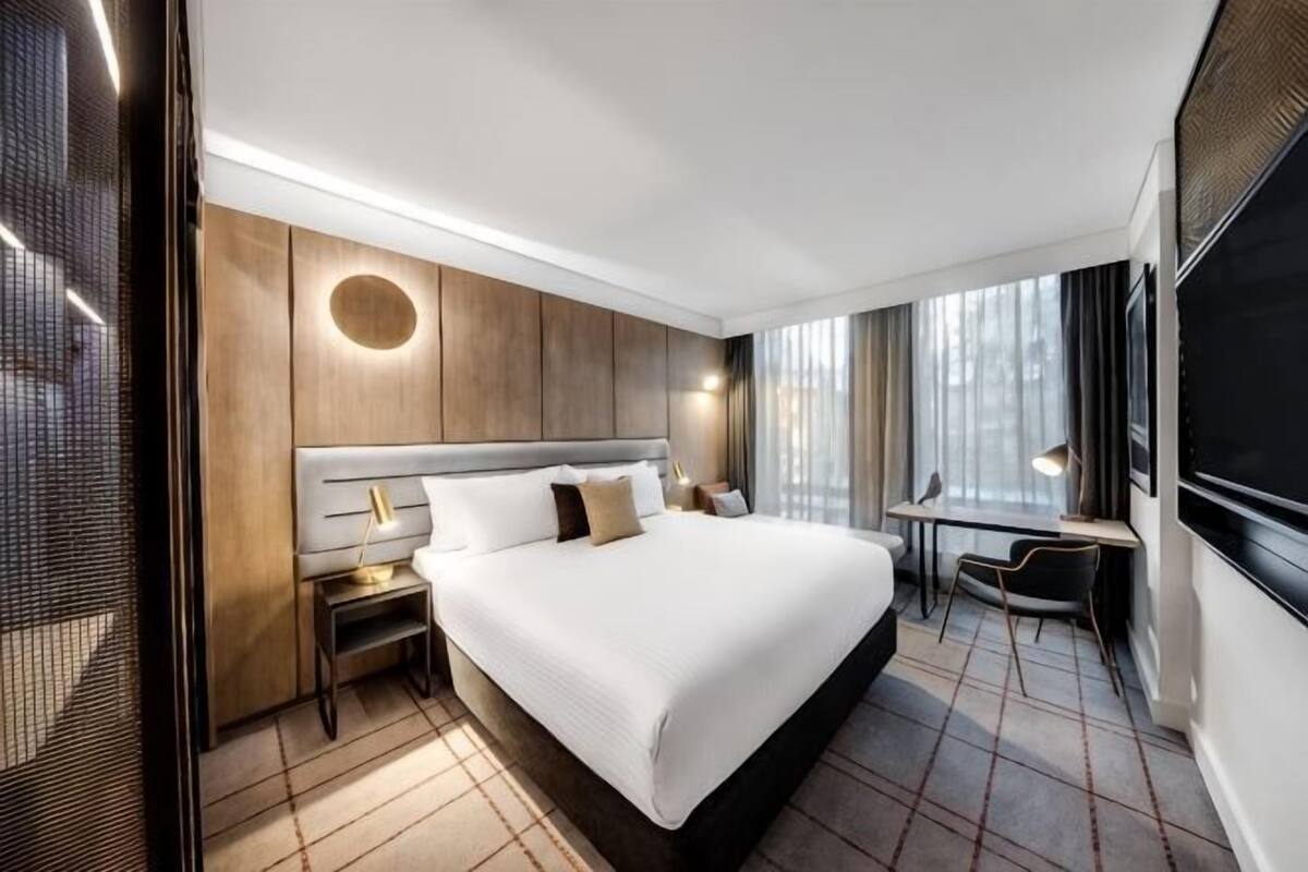 Een moderne hotelkamer met een groot bed, een bureau en uitzicht op de stad.