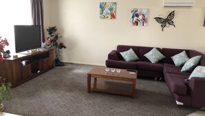 A living room with a TV, sofa, coffee table, and artwork on the walls.