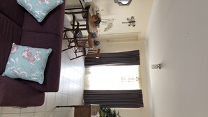 A living room with a sofa, a dining table with chairs, a small cabinet, and a decorative butterfly on the wall.