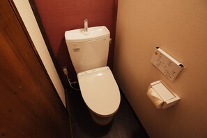A standard toilet with a flush handle, a toilet paper holder, and a wall-mounted flush button. - Kotone Machiya Inn (Kyoto)