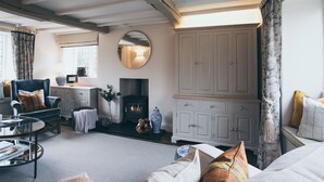 Un salon chaleureux avec une cheminée, une grande armoire blanche et un coin salon confortable.