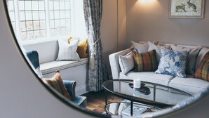 Un salon chaleureux avec un canapé, une table basse et une fenêtre donnant sur un beau paysage.