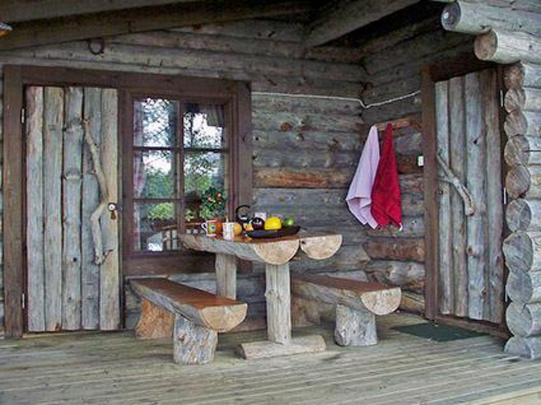A rustic wooden cabin with a wooden bench and a table with a fruit bowl.