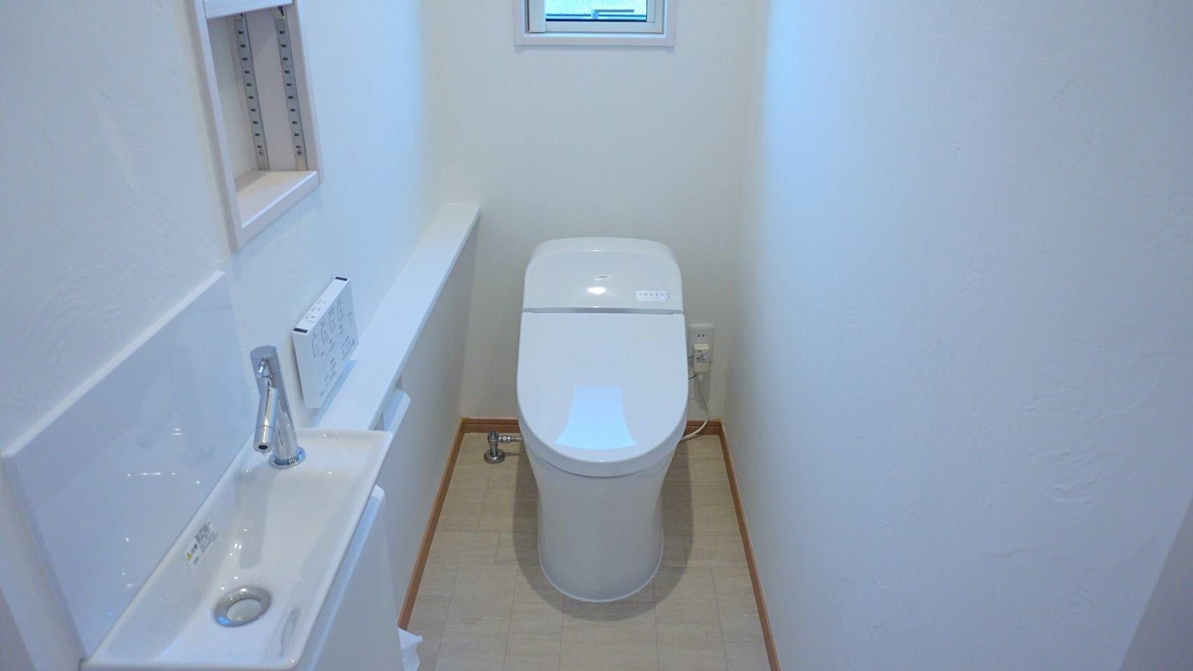 Un baño pequeño y limpio con inodoro, lavamanos y ventana sobre el inodoro.