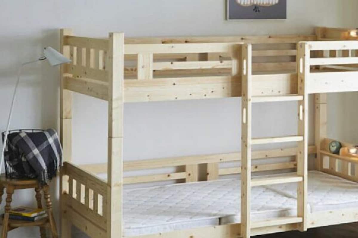 A bunk bed with a wooden frame, a desk with a lamp, and a chair.