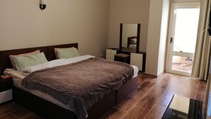A bedroom with a bed, bedside table, dresser, mirror, and a view of the outside through a window. - Well equipped apartment in Hurghada (Hurghada)
