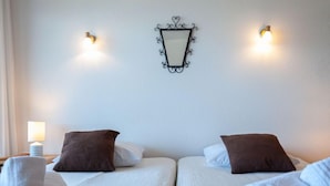Ett hotellrum med två sängar, var och en med en brun och en vit kudde. Det finns handdukar på sängarna och en väggmonterad lampa ovanför sängarna.