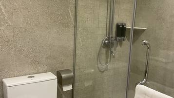 Un baño moderno con ducha de vidrio, inodoro y barra para toallas.