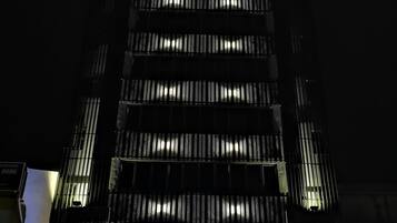 Un hotel llamado "FRAME HOTEL" con una fachada moderna, varios pisos y un letrero iluminado destacado.