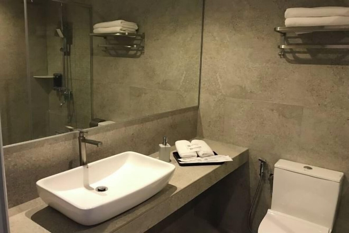 Une salle de bain moderne avec un grand lavabo, un miroir, des toilettes et un porte-serviettes.
