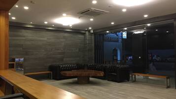En moderne lobby med en træreception, lædersofaer og et stort kaffebord.