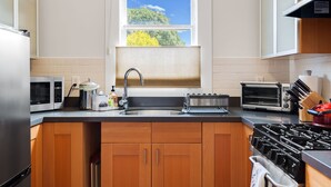 A modern kitchen with wooden cabinets, a stainless steel sink, a microwave, a toaster, and a stove. - Quiet, Comfortable & Clean. Easy Access to SF, Berkeley, Contra Costa (Oakland)