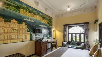 A hotel room with a large mural, a bed, a desk, and a window with a view.