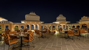 An outdoor dining area with tables and chairs, surrounded by ornate architecture.