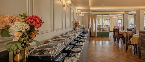 Ein Buffetbereich mit einer langen Theke, verschiedenen Servierstationen und einem Essbereich mit Tischen und Stühlen.