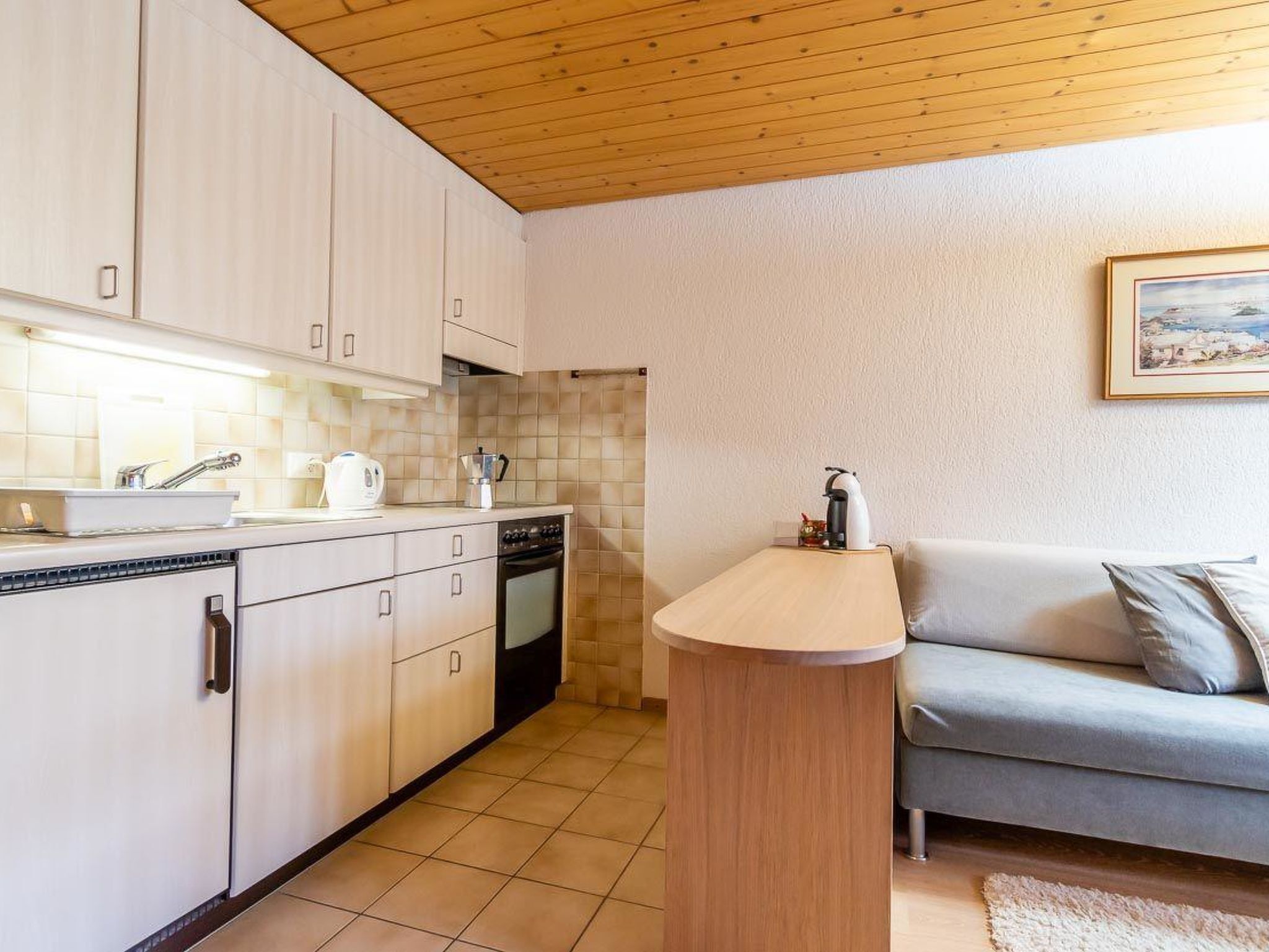 Una cocina compacta con armarios blancos, horno empotrado y una pequeña isla.