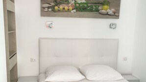 Ein Schlafzimmer mit einem Bett, zwei Nachttischen, einem Holzregal und einem Wandbild.