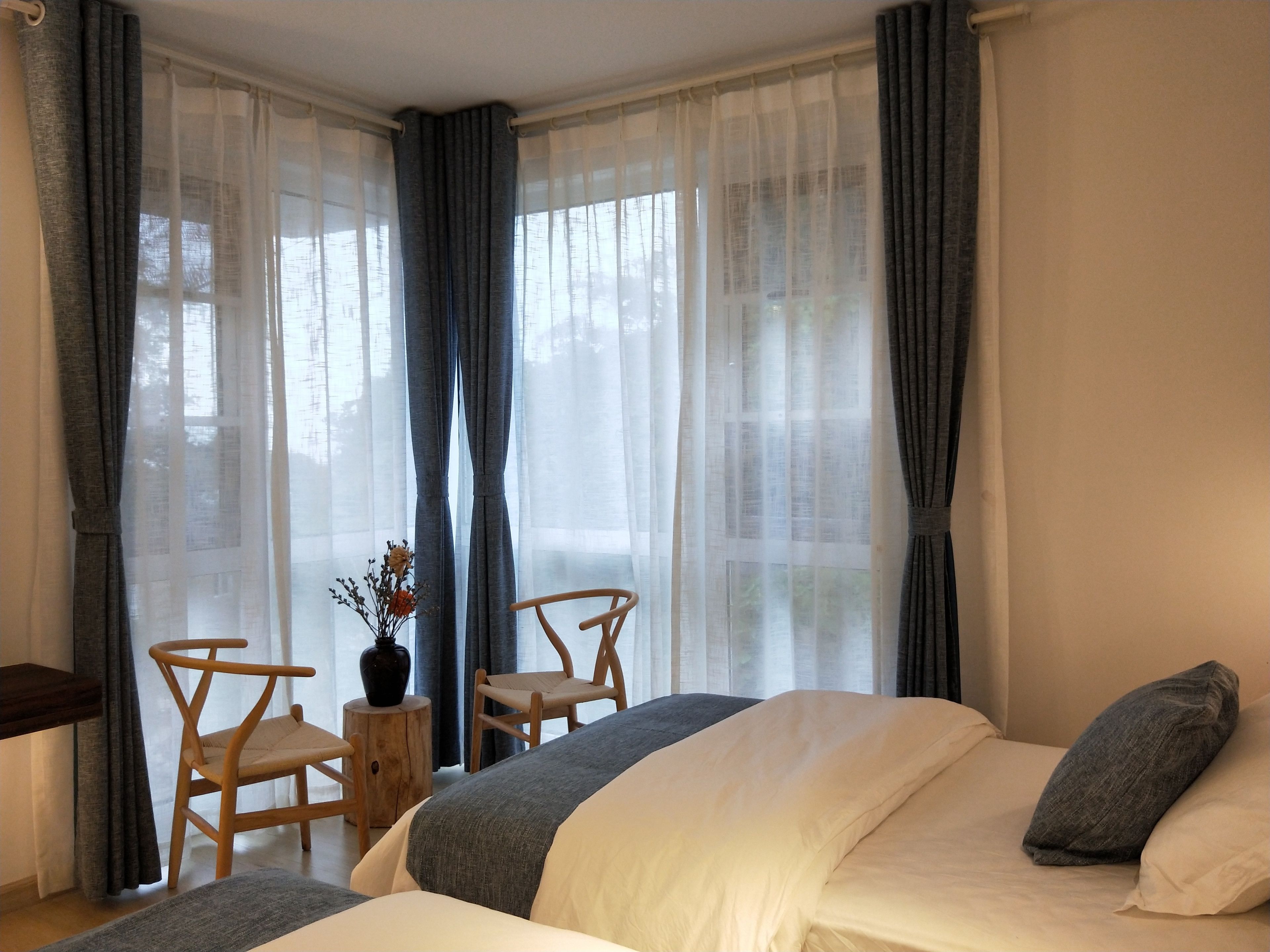 Une chambre à coucher avec un lit, deux chaises, une petite table et un vase de fleurs.