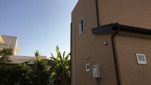 Ein Backsteinhaus mit vielen Fenstern und einem sichtbaren Stromkasten an der Seite.