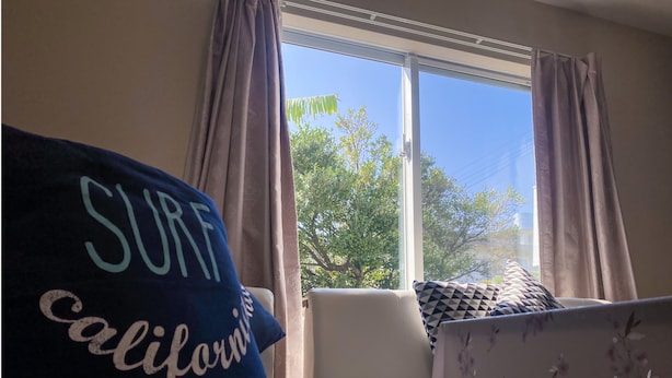 Ein Zimmer mit Fenster, einer Couch und einem Kissen mit dem Aufdruck 'SURF California'.