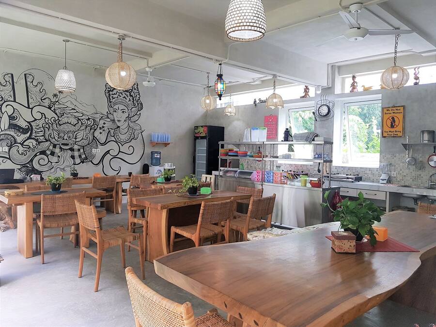 Un restaurante con mesas y sillas de madera, luces colgantes y un mural en la pared.