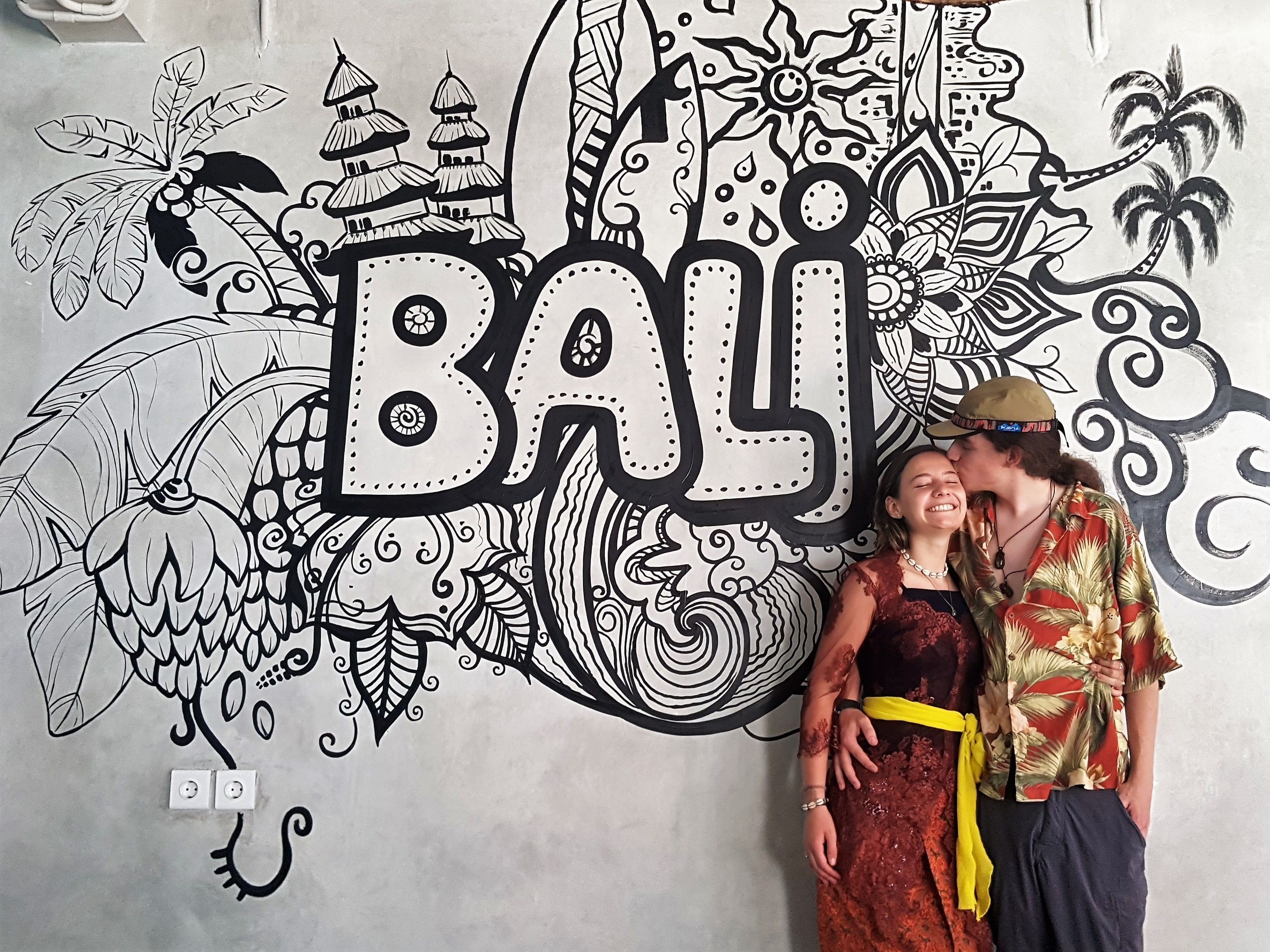 Una pared con un gran letrero que dice 'Bali', rodeada de intrincados diseños en blanco y negro.