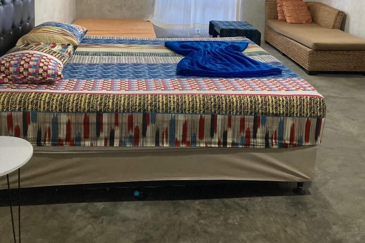 Ein Schlafzimmer mit einem Bett, einem Sofa, einem Sessel und einem Fenster mit Vorhängen.