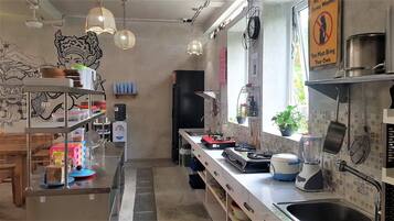 Una cocina con una encimera larga, electrodomésticos diversos e iluminación colgante.