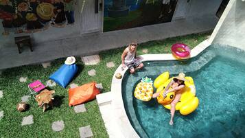 A swimming pool with inflatable toys, a mural on the wall, and a small table with a drink.